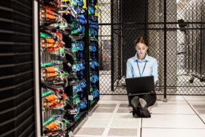 Caucasian woman technician working on computer servers in a server farm.